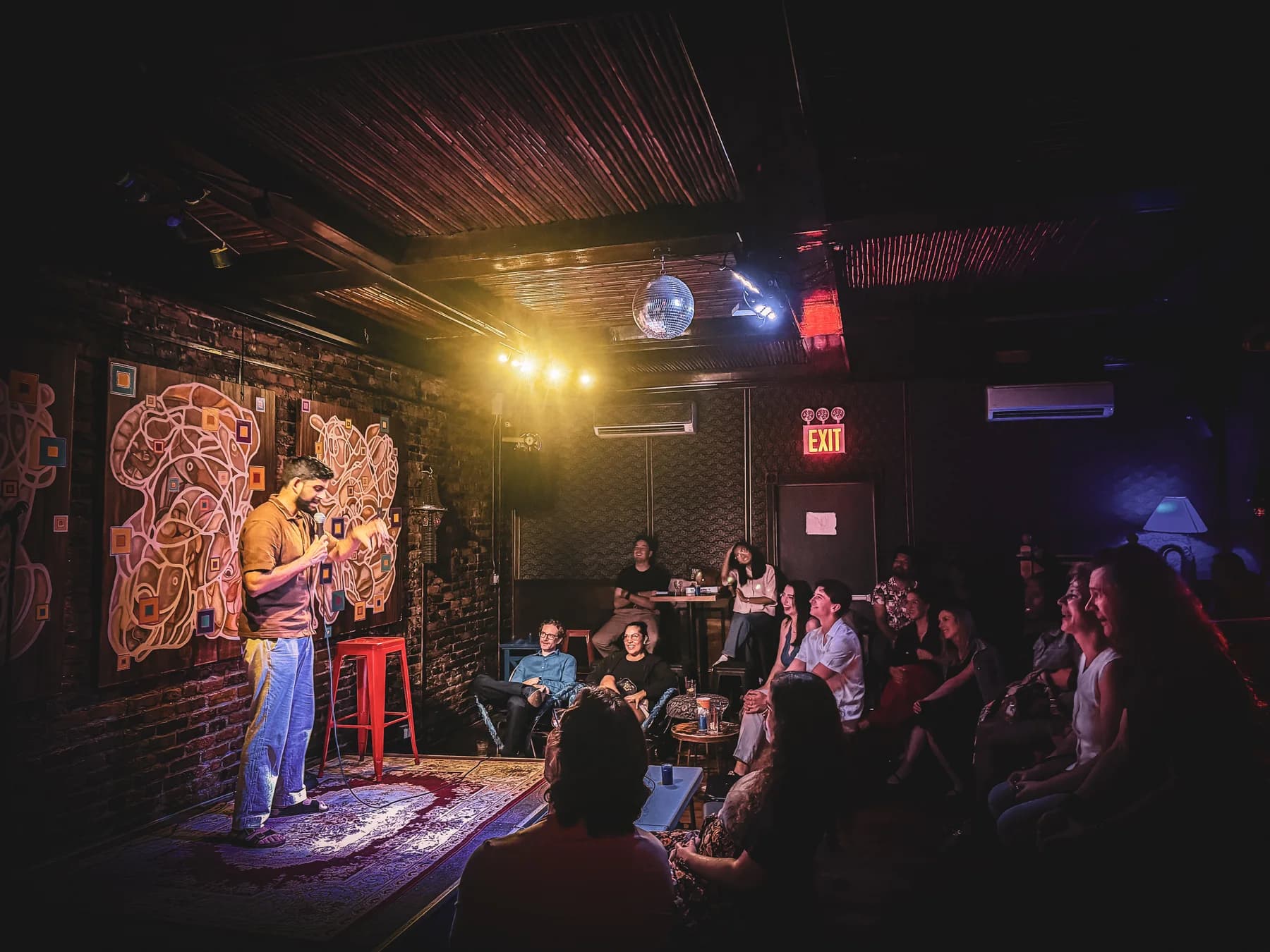A comedian performs close to the audience in Revision Lounge’s warmly lit room